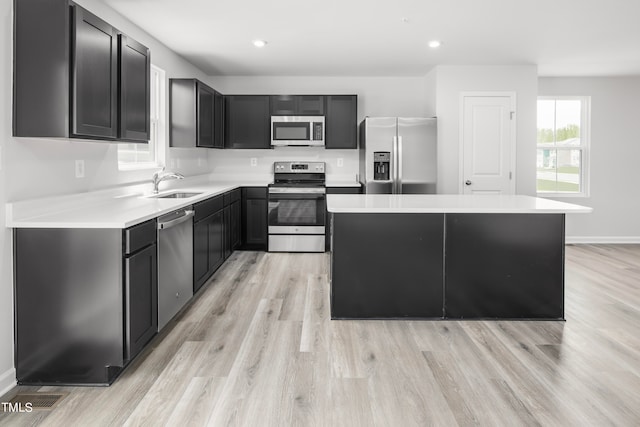 kitchen with light hardwood / wood-style floors, stainless steel appliances, sink, and a kitchen island