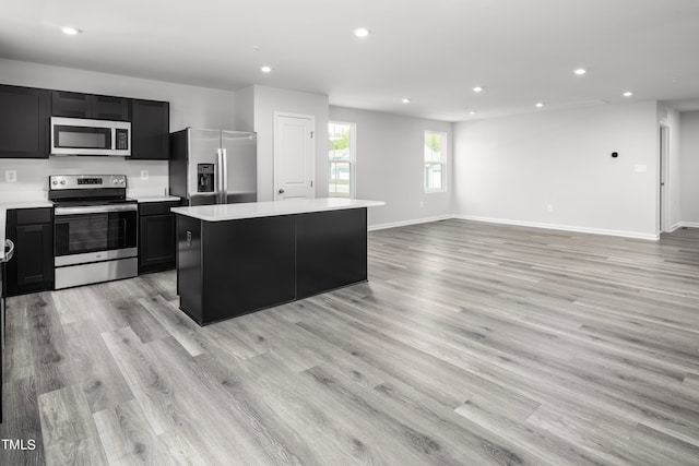 kitchen featuring a kitchen island, stainless steel appliances, and light wood-type flooring