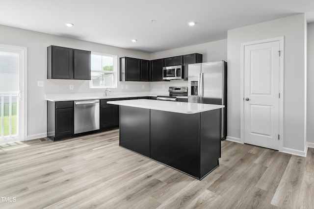 kitchen with stainless steel appliances, sink, light wood-type flooring, and a kitchen island