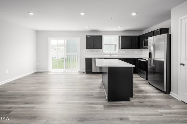 kitchen featuring a center island, stainless steel appliances, sink, and light wood-type flooring