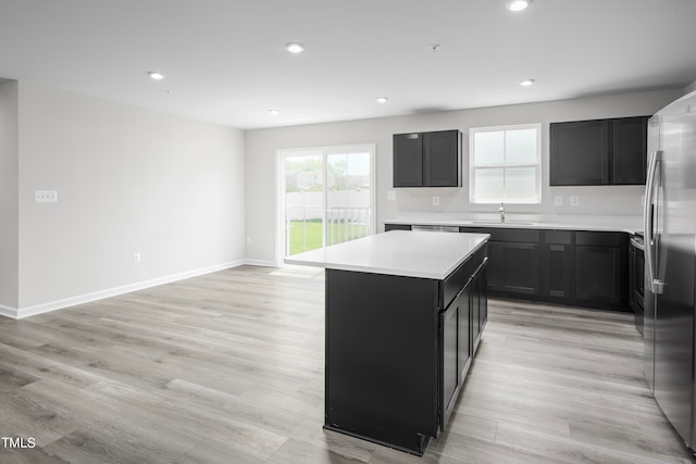 kitchen featuring sink, light hardwood / wood-style floors, a center island, and stainless steel fridge