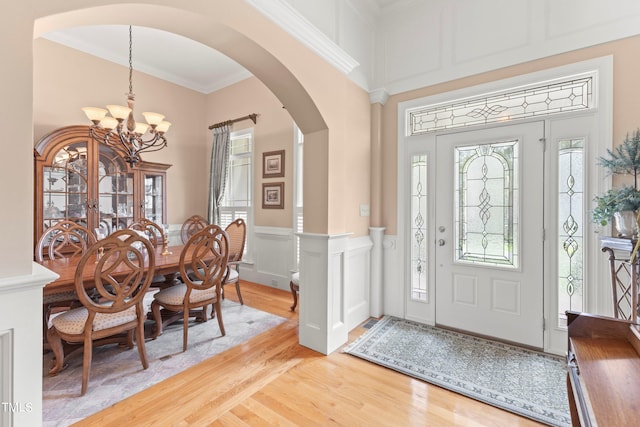 foyer entrance featuring light hardwood / wood-style floors, a notable chandelier, and ornamental molding