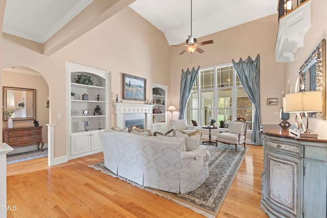 living room with light hardwood / wood-style floors, ornamental molding, high vaulted ceiling, and ceiling fan