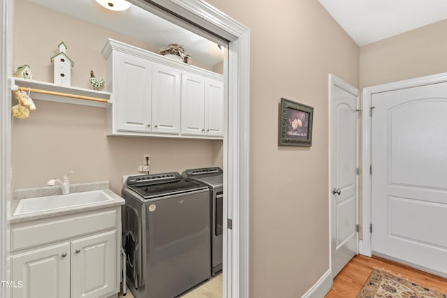 washroom featuring light hardwood / wood-style floors, sink, cabinets, and washing machine and dryer