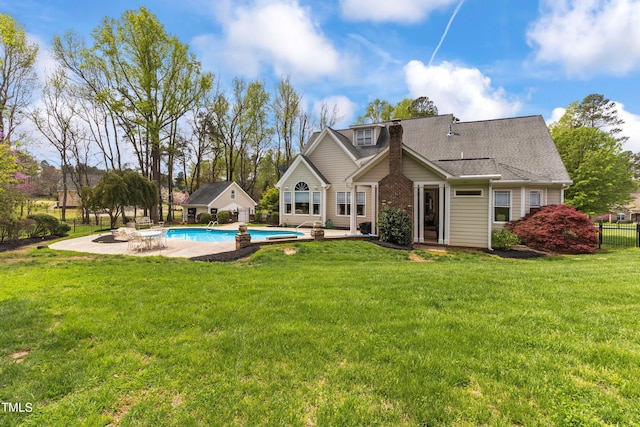 rear view of house with a patio, a lawn, and a fenced in pool