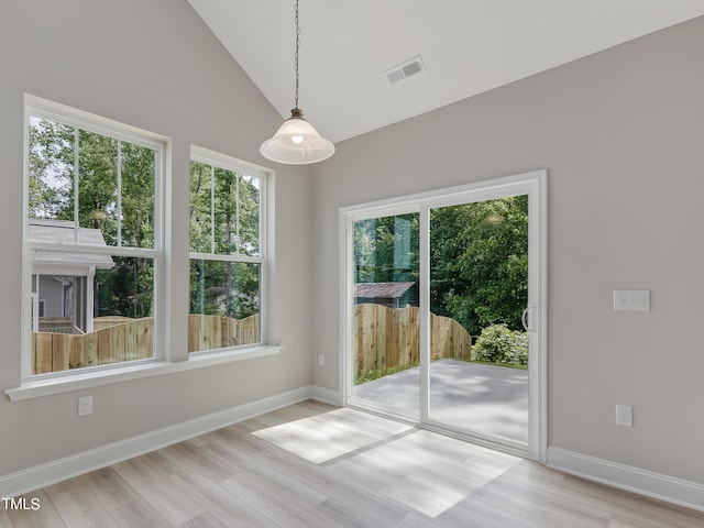 unfurnished dining area with plenty of natural light, light hardwood / wood-style floors, and vaulted ceiling