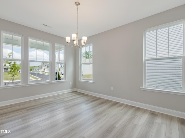 empty room featuring a chandelier and light wood-type flooring