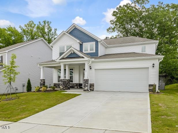 craftsman house featuring central AC, a garage, covered porch, and a front lawn