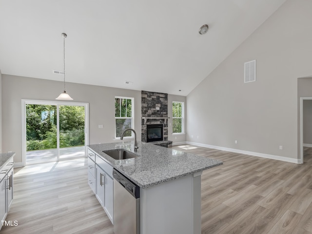 kitchen with stainless steel dishwasher, pendant lighting, light wood-type flooring, and sink