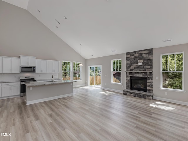 kitchen featuring white cabinets, appliances with stainless steel finishes, light stone counters, and a wealth of natural light