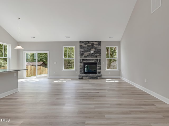 unfurnished living room with light wood-type flooring, lofted ceiling, and a fireplace