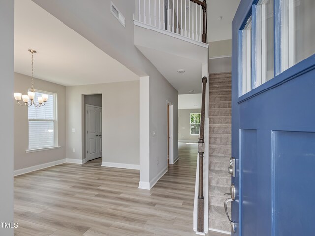 foyer entrance featuring light wood-type flooring, plenty of natural light, and a notable chandelier