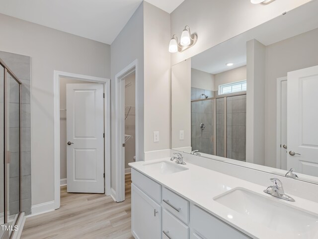 bathroom with hardwood / wood-style floors, vanity, and an enclosed shower