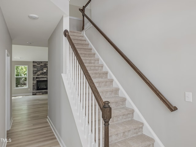 stairway featuring a stone fireplace and hardwood / wood-style floors