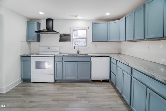 kitchen with wall chimney range hood, white appliances, sink, light stone counters, and light hardwood / wood-style floors