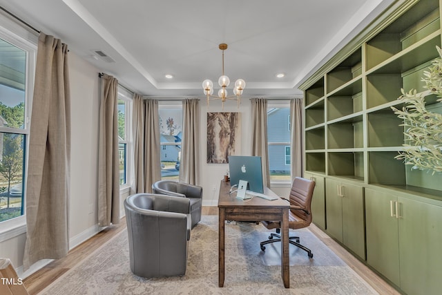 office with light wood-style flooring, visible vents, a tray ceiling, baseboards, and an inviting chandelier