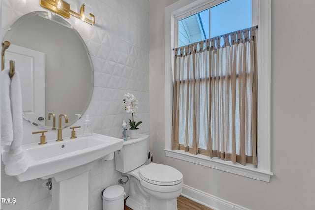 bathroom featuring tile walls, baseboards, and toilet