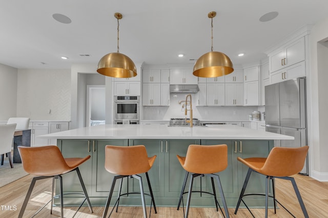 kitchen with tasteful backsplash, a large island with sink, range hood, and pendant lighting