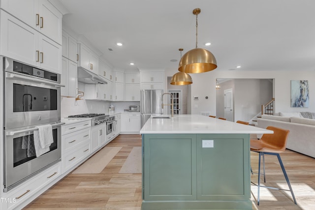 kitchen with under cabinet range hood, white cabinets, appliances with stainless steel finishes, and light wood finished floors