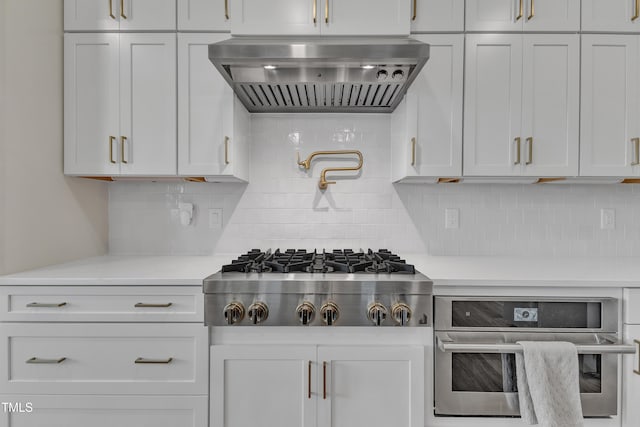 kitchen with decorative backsplash, white cabinetry, appliances with stainless steel finishes, and extractor fan