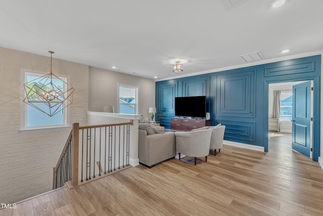 living room with light hardwood / wood-style floors, ornamental molding, and a chandelier