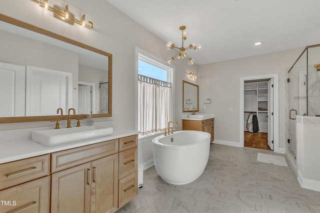 bathroom featuring a chandelier, a stall shower, a freestanding bath, and a sink