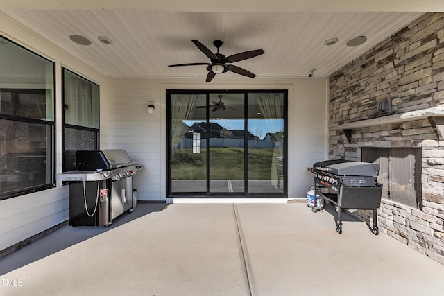 view of patio featuring grilling area, an outdoor stone fireplace, and a ceiling fan