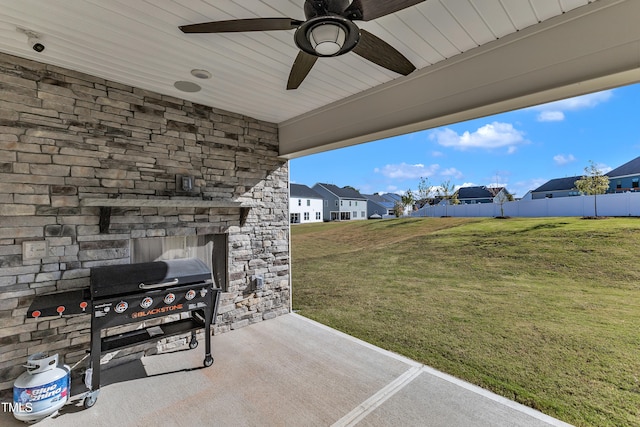 view of patio featuring ceiling fan, an outdoor stone fireplace, and area for grilling