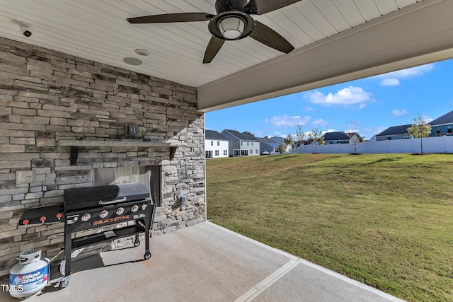 view of patio / terrace featuring a residential view, an outdoor stone fireplace, ceiling fan, fence, and a grill