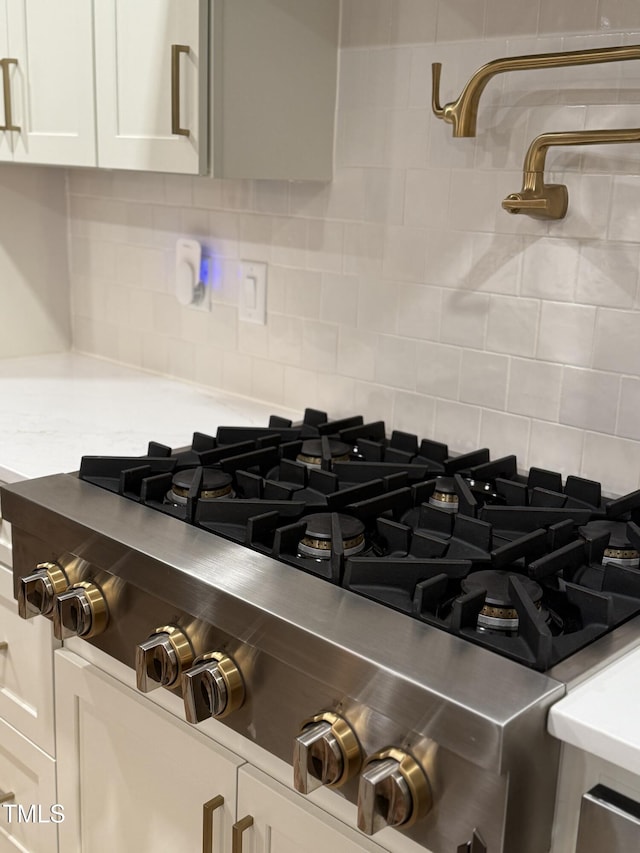 details featuring white cabinets, range, and tasteful backsplash