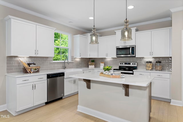 kitchen featuring white cabinets, a kitchen island, appliances with stainless steel finishes, pendant lighting, and sink