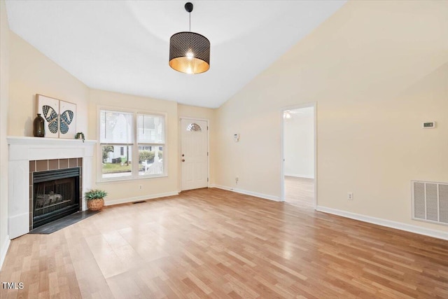 unfurnished living room featuring high vaulted ceiling, light wood-type flooring, and a fireplace