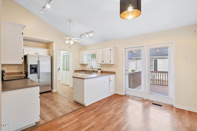 kitchen featuring stainless steel refrigerator with ice dispenser, vaulted ceiling, light wood-type flooring, white cabinetry, and ceiling fan