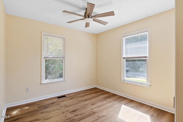 spare room featuring a textured ceiling, light hardwood / wood-style floors, and ceiling fan