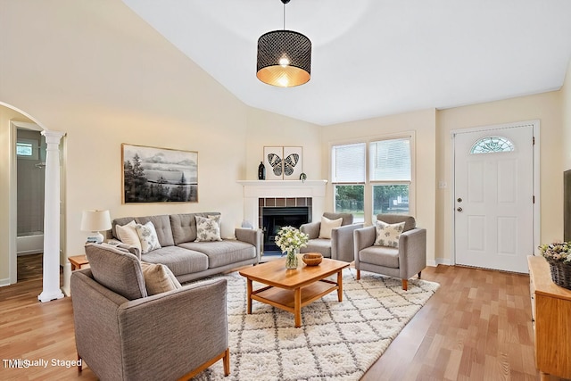 living room featuring ornate columns, light hardwood / wood-style floors, high vaulted ceiling, and a fireplace