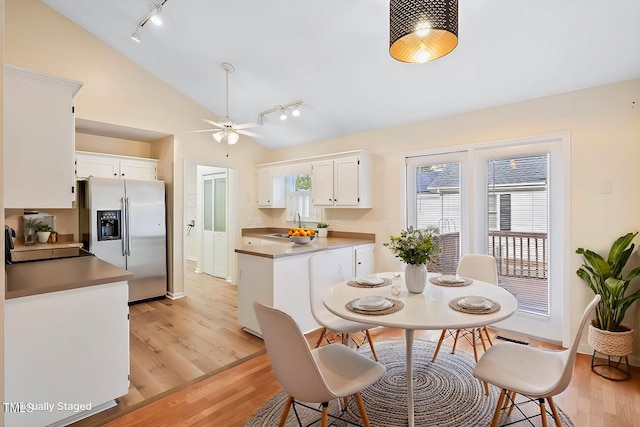 kitchen featuring white cabinetry, vaulted ceiling, plenty of natural light, and stainless steel fridge