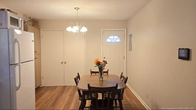 dining space featuring an inviting chandelier, a textured ceiling, and wood-type flooring