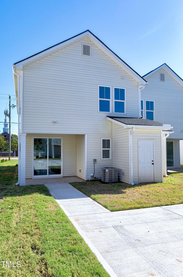 back of property featuring central AC unit and a lawn