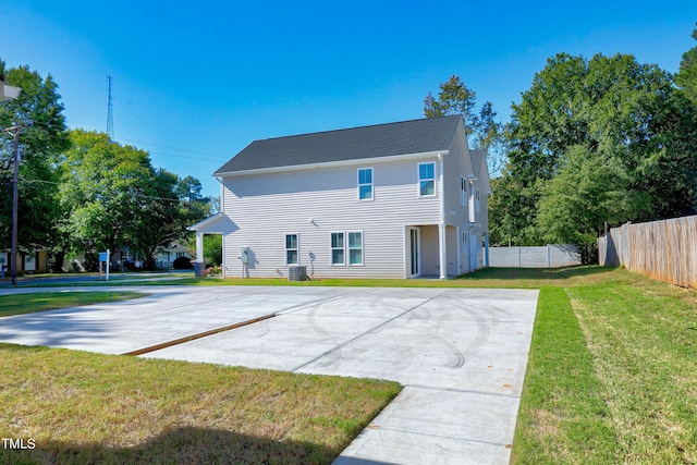 rear view of property featuring a yard and central AC unit