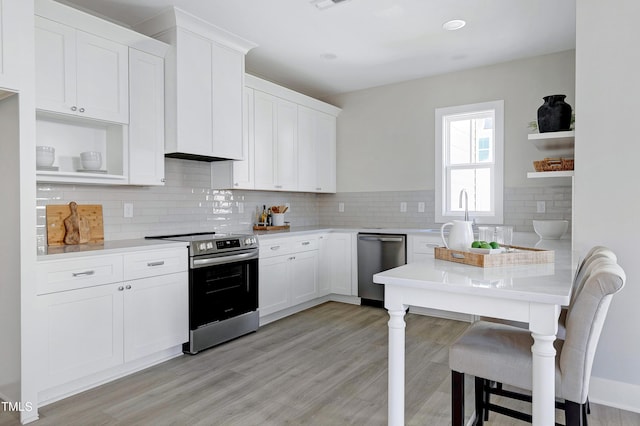 kitchen featuring backsplash, white cabinetry, stainless steel appliances, and light hardwood / wood-style floors