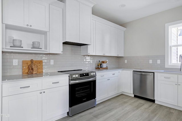 kitchen featuring white cabinetry, light hardwood / wood-style floors, stainless steel appliances, and decorative backsplash