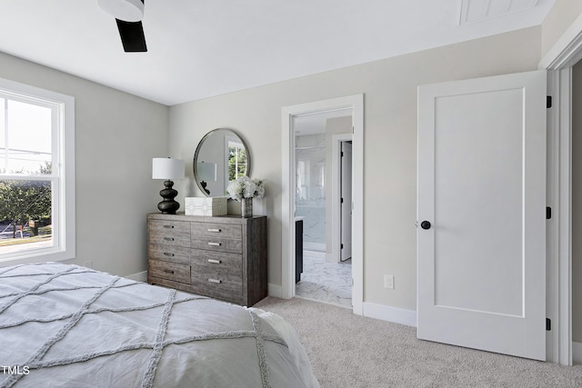 carpeted bedroom with ensuite bathroom, multiple windows, and ceiling fan