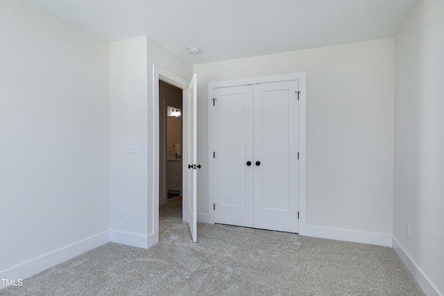 unfurnished bedroom with light colored carpet and a closet