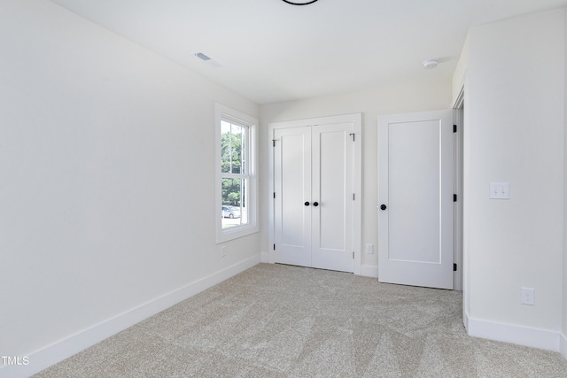 unfurnished bedroom featuring light carpet and a closet