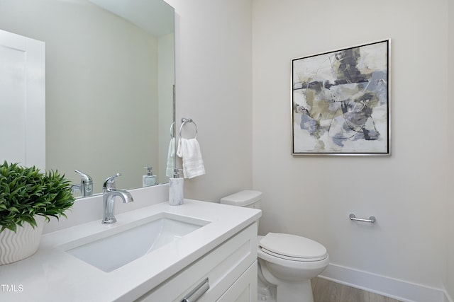 bathroom with toilet, vanity, and wood-type flooring