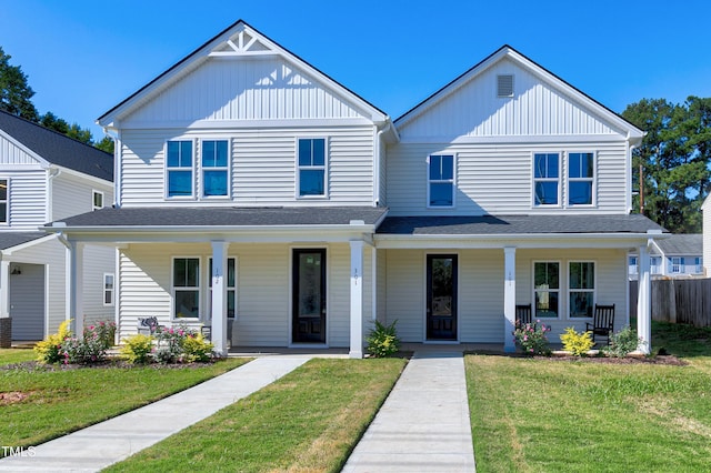 view of front facade featuring board and batten siding, a front yard, a porch, and a shingled roof