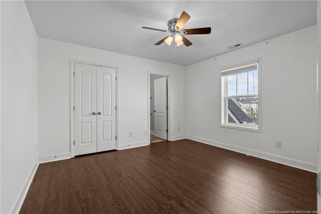 unfurnished bedroom with dark hardwood / wood-style flooring, a closet, and ceiling fan