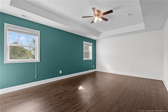 unfurnished room featuring ceiling fan, a tray ceiling, and dark hardwood / wood-style flooring