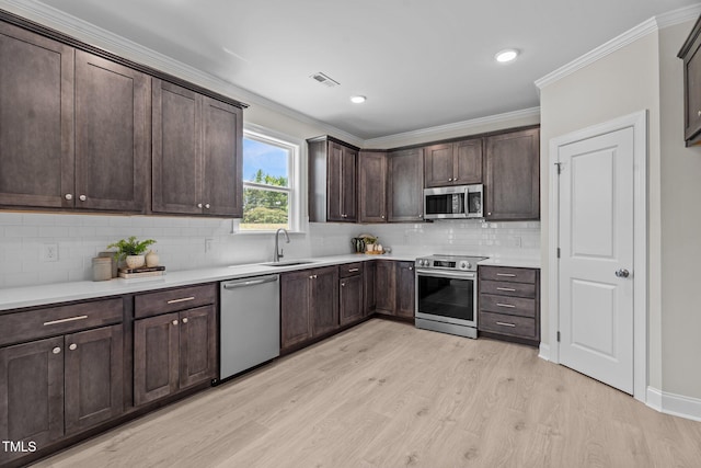 15 Diamond Creek Dr, Zebulon, NC 27597 - kitchen featuring appliances with stainless steel finishes, light wood finished floors, dark brown cabinets, crown molding, and backsplash