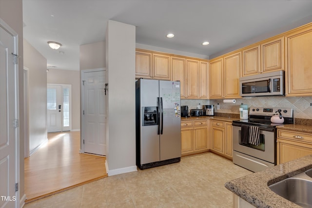 kitchen with stainless steel appliances, light hardwood / wood-style floors, stone countertops, light brown cabinetry, and decorative backsplash